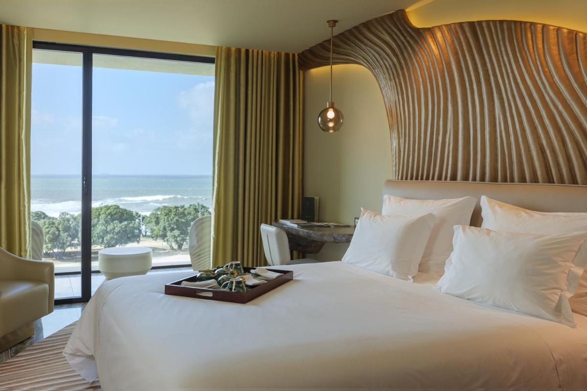 um quarto com uma grande cama branca e uma grande janela em Vila Foz Hotel & SPA - member of Design Hotels no Porto