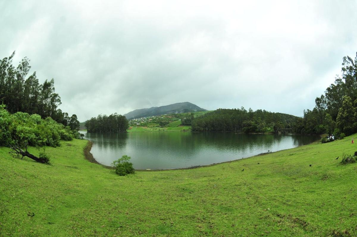 a view of a lake in a field with a hill in the background at Savoy - IHCL SeleQtions in Ooty