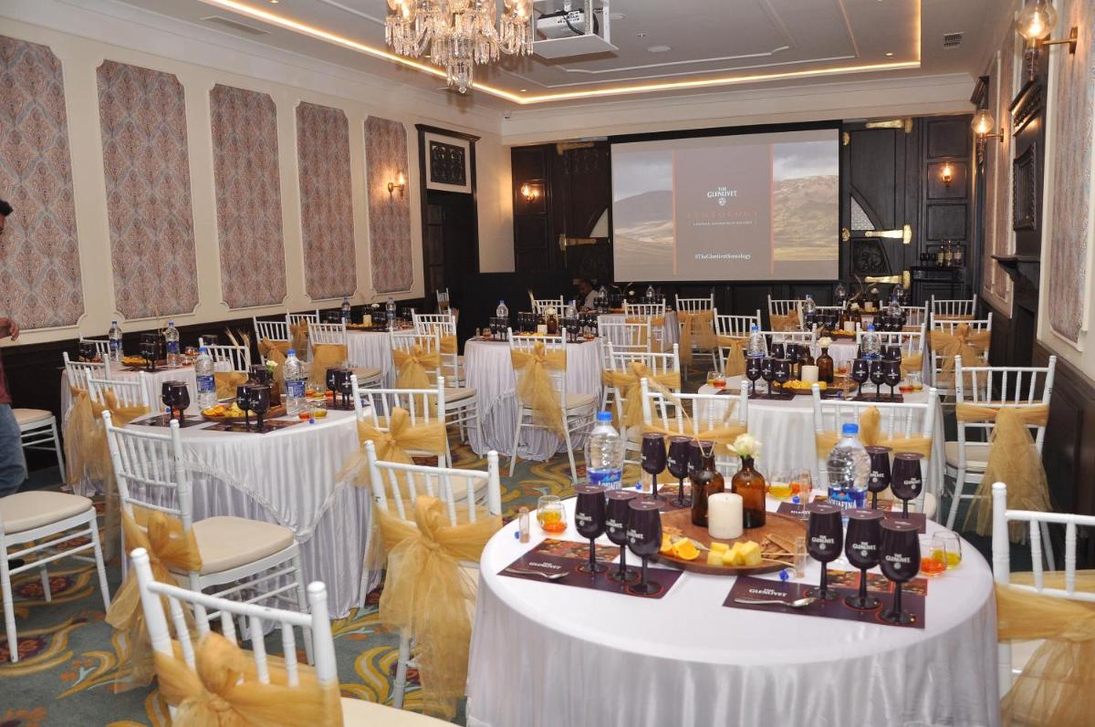 a conference room with white tables and chairs and a screen at Savoy - IHCL SeleQtions in Ooty