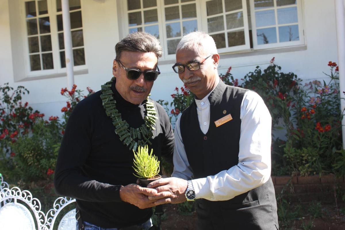 two men standing next to each other holding a plant at Savoy - IHCL SeleQtions in Ooty
