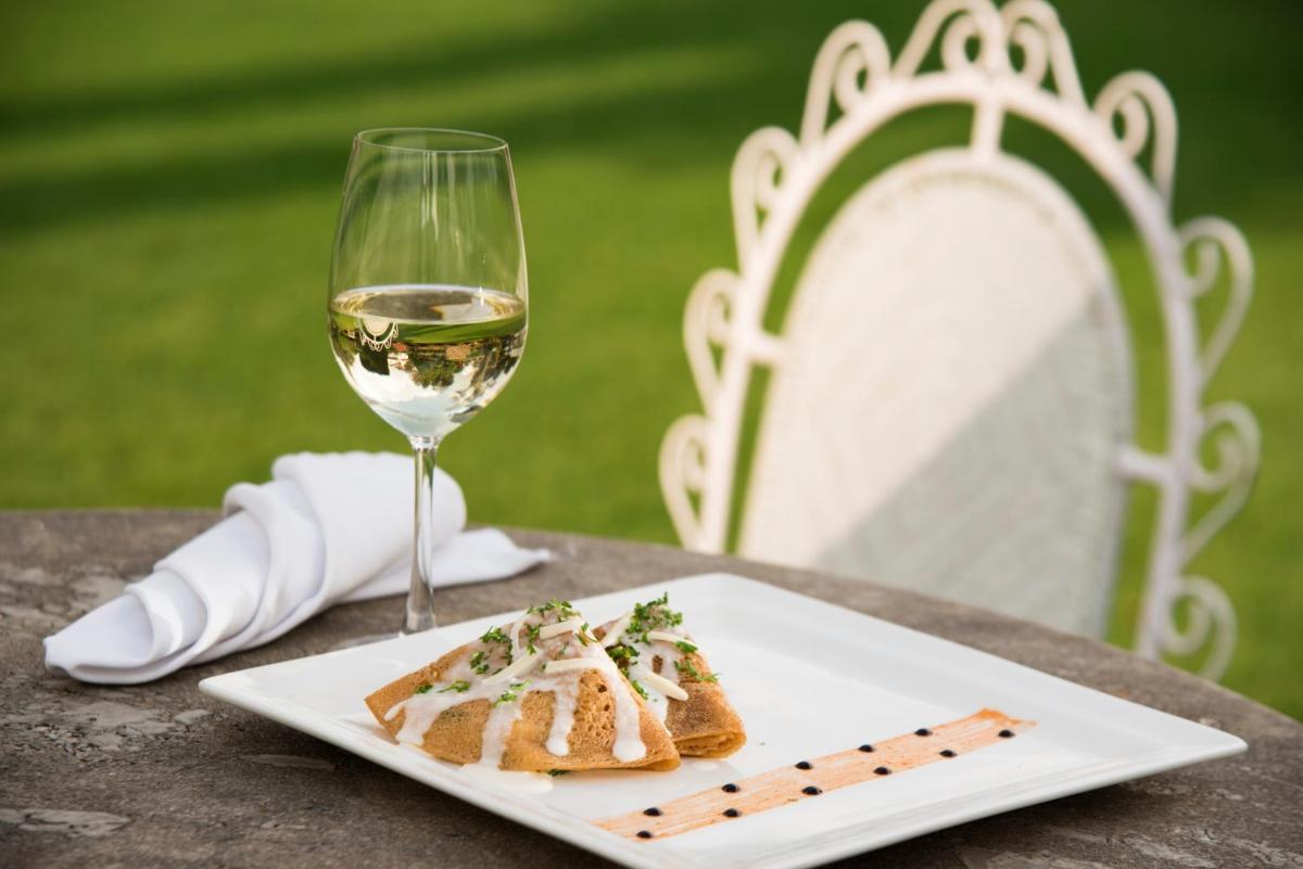 a plate of food and a glass of wine on a table at Savoy - IHCL SeleQtions in Ooty