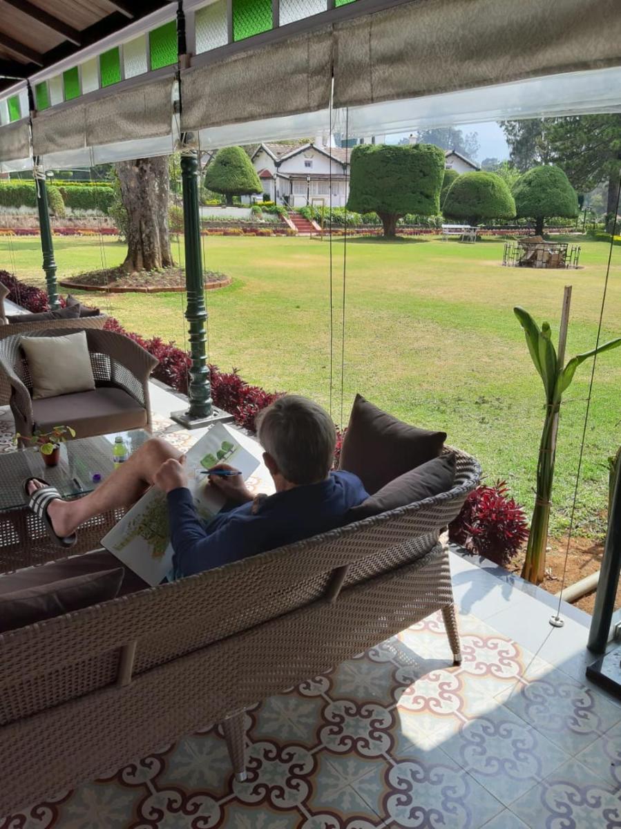 a man sitting on a bench reading a book at Savoy - IHCL SeleQtions in Ooty