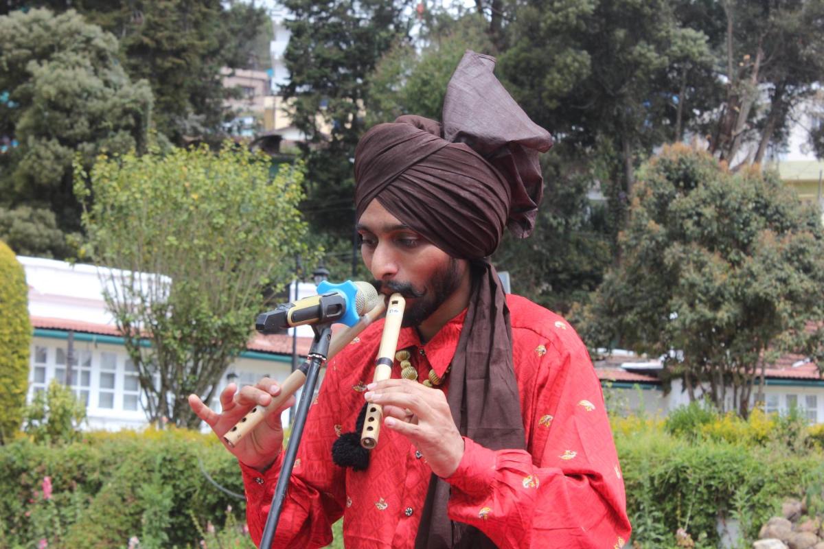 a man singing into a microphone while holding a stick at Savoy - IHCL SeleQtions in Ooty
