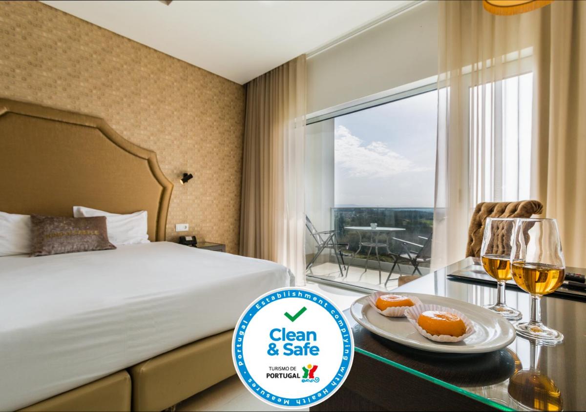 um quarto de hotel com uma cama e uma mesa com taças de vinho em Lisotel - Hotel & Spa em Leiria