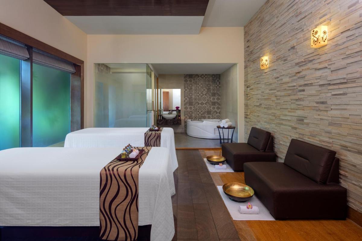a bedroom with a bed and a living room at Radisson Blu Plaza Hotel Mysore in Mysore