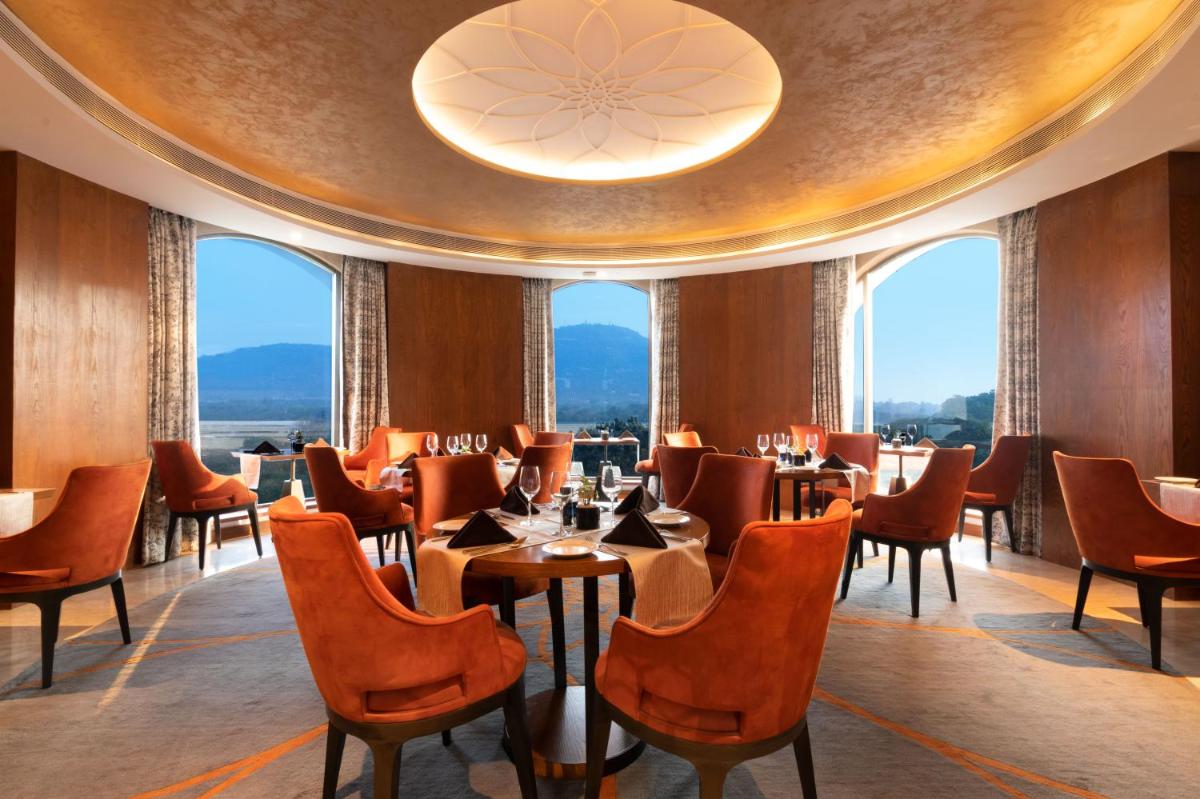 a restaurant with tables and chairs and windows at Radisson Blu Plaza Hotel Mysore in Mysore