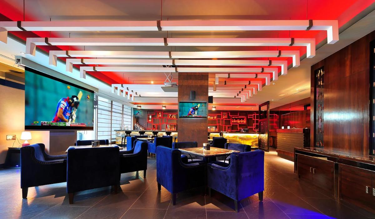a restaurant with tables and chairs and a large screen at Radisson Blu Plaza Hotel Mysore in Mysore