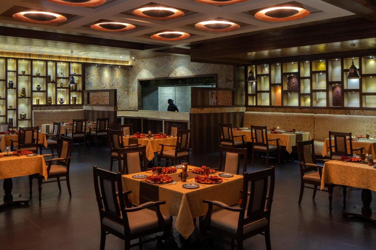a restaurant with tables and chairs in a room at Radisson Blu Plaza Hotel Mysore in Mysore