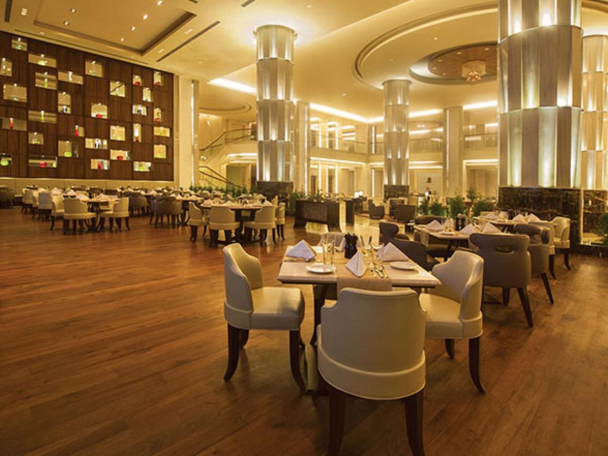 a restaurant with tables and chairs in a room at Radisson Blu Plaza Hotel Mysore in Mysore