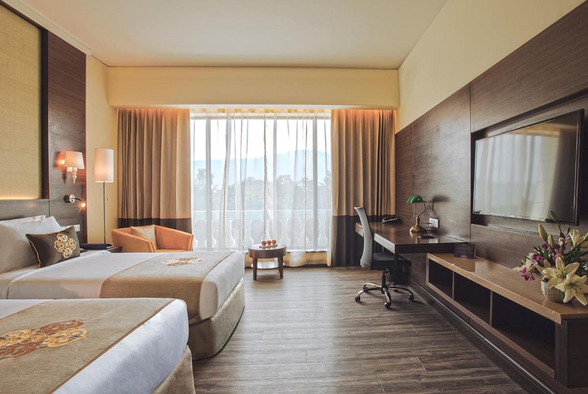 a hotel room with two beds and a television at Radisson Blu Plaza Hotel Mysore in Mysore