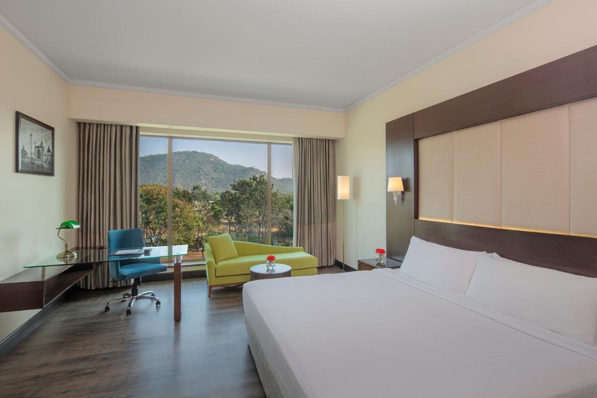 a hotel room with a large bed and a desk at Radisson Blu Plaza Hotel Mysore in Mysore