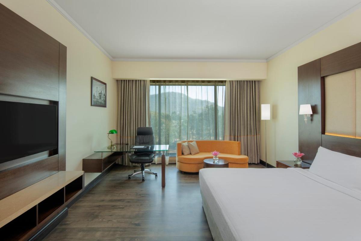 a hotel room with a bed and a couch and a table at Radisson Blu Plaza Hotel Mysore in Mysore
