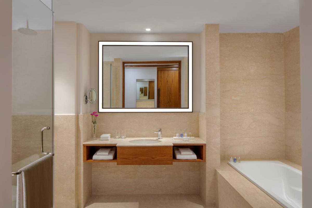 a bathroom with a sink and a tub and a mirror at Radisson Blu Plaza Hotel Mysore in Mysore