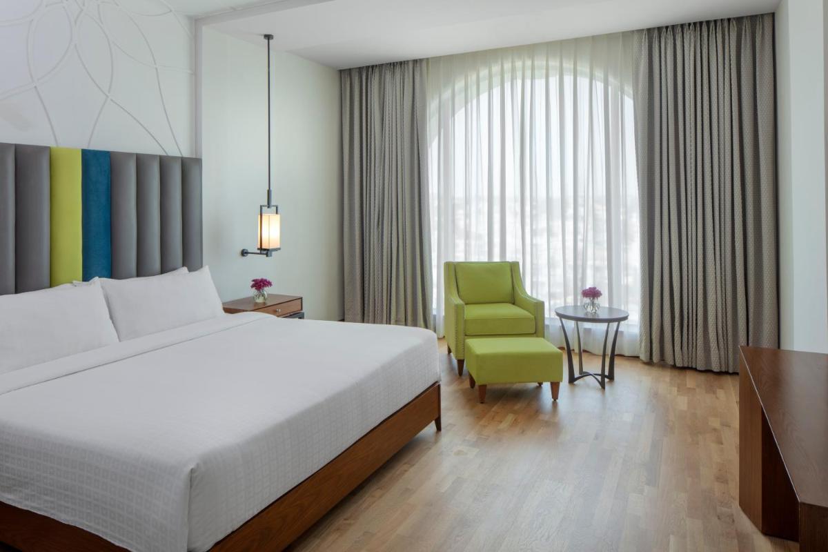 a bedroom with a bed and a green chair at Radisson Blu Plaza Hotel Mysore in Mysore