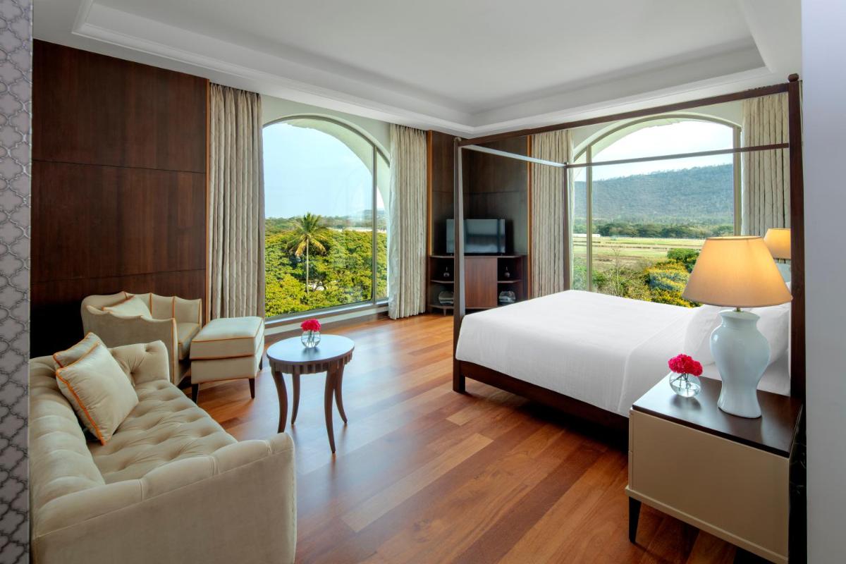 a hotel room with a bed and a couch and a window at Radisson Blu Plaza Hotel Mysore in Mysore