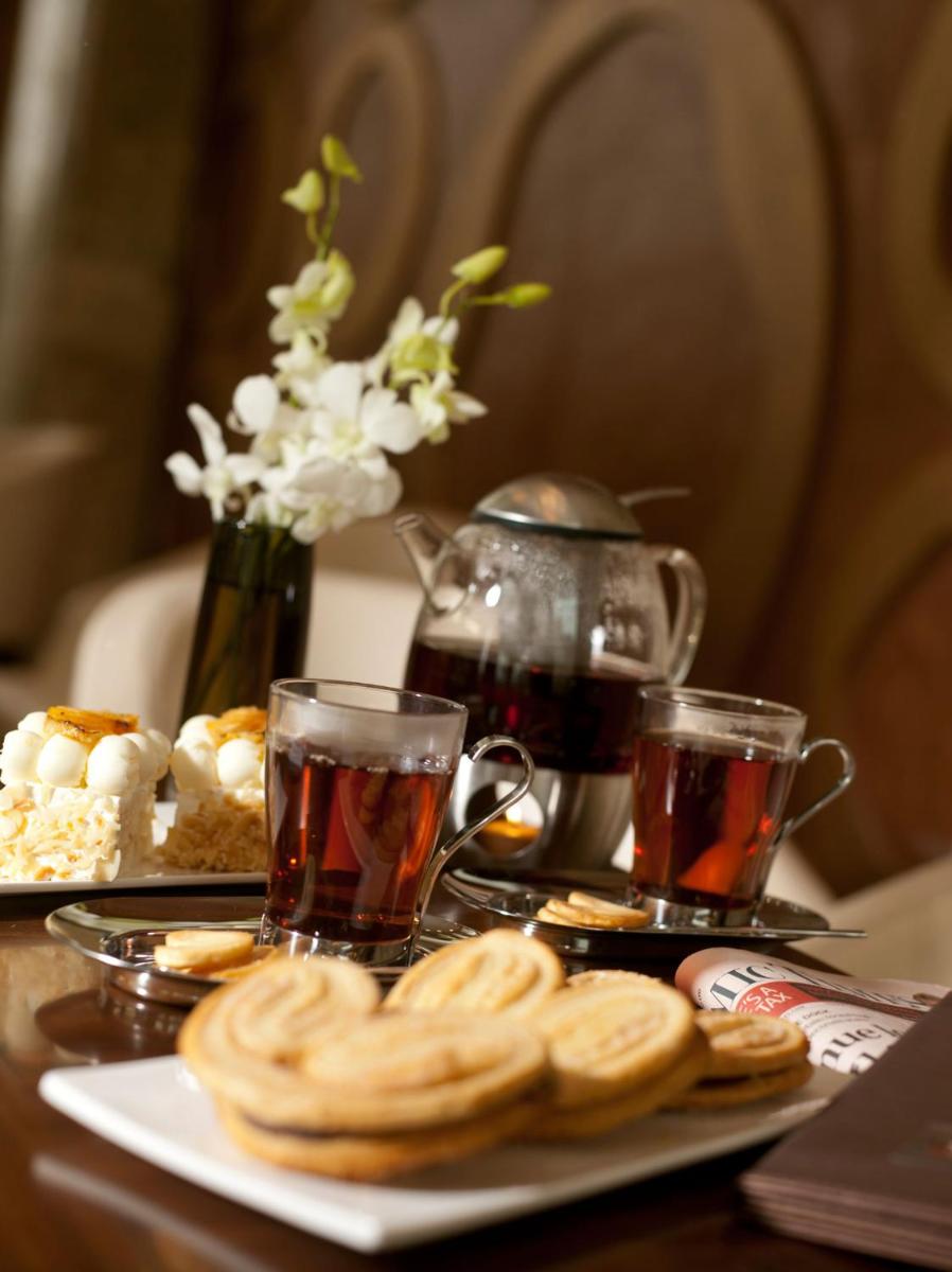 a table with two cups of tea and a plate of food at Crowne Plaza New Delhi Okhla by IHG in New Delhi