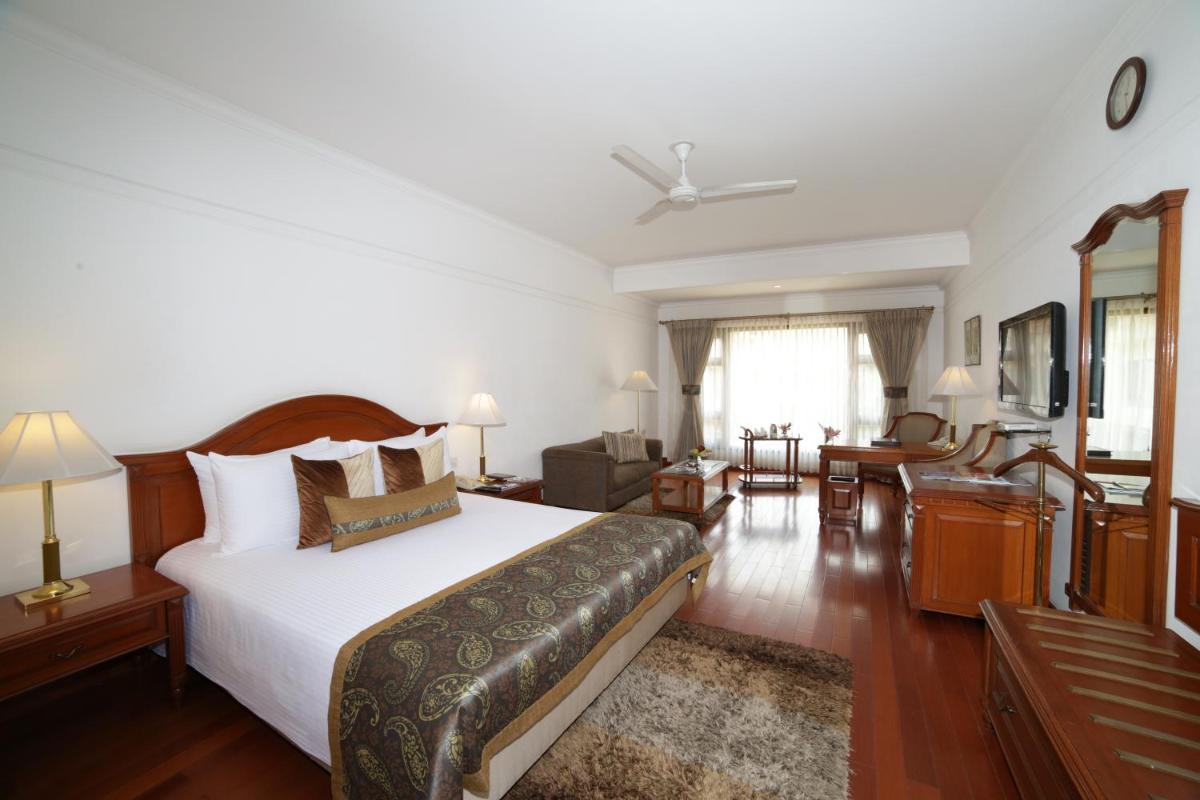 a bedroom with a large bed and a living room at Jaypee Palace Hotel in Agra