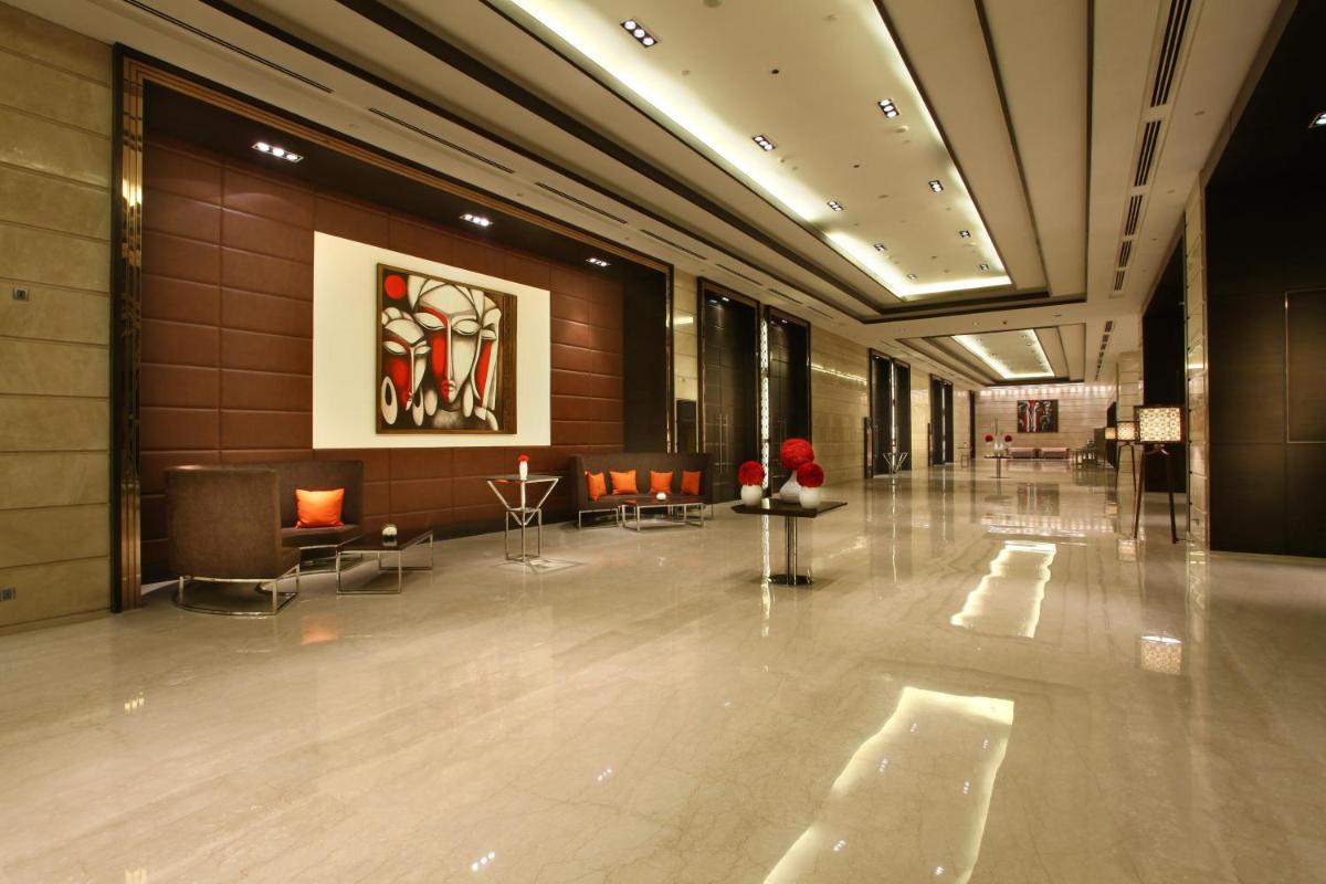 a lobby with chairs and a painting on the wall at Crowne Plaza New Delhi Rohini by IHG in New Delhi a lobby with chairs and a painting on the wall at Crowne Plaza New Delhi Rohini by IHG in New Delhi