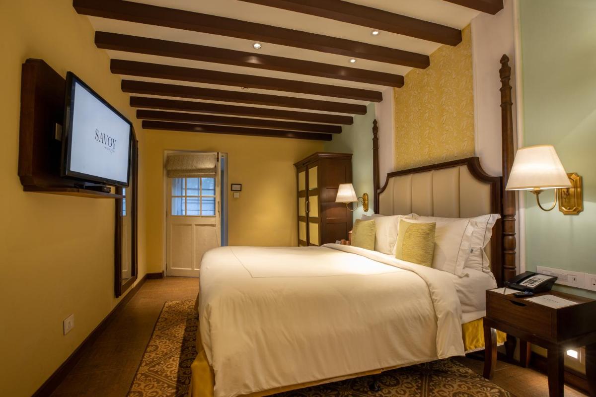 a bedroom with a large bed and a flat screen tv at Savoy - IHCL SeleQtions in Ooty