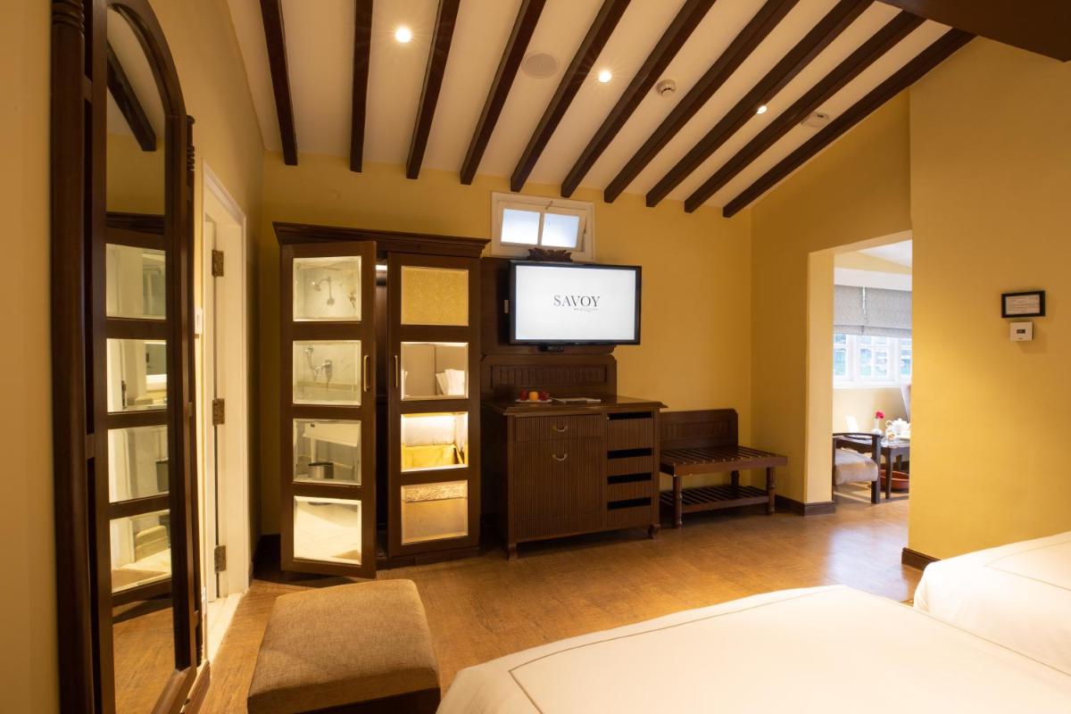 a bedroom with a tv on a dresser with a bed at Savoy - IHCL SeleQtions in Ooty