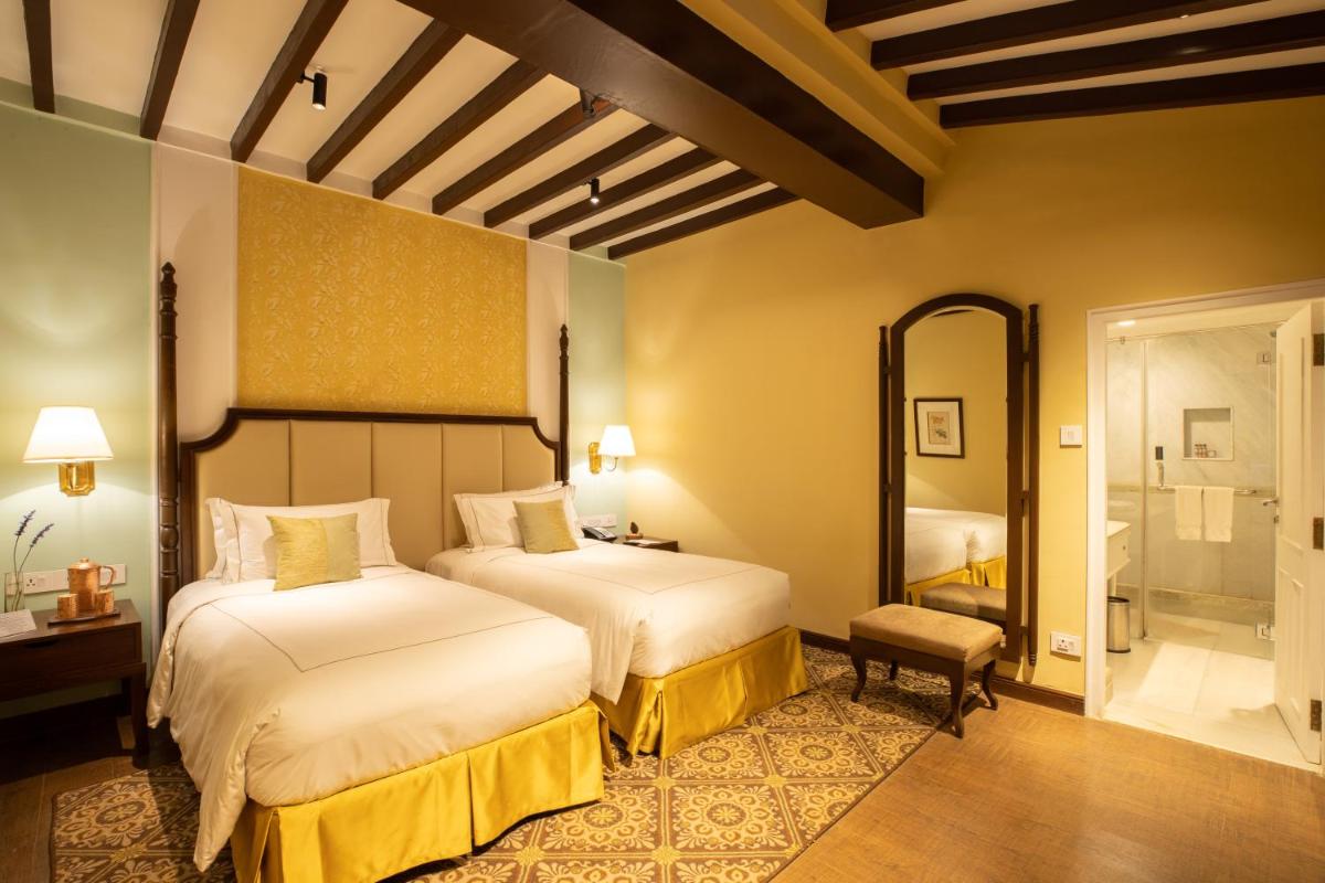 a hotel room with two beds and a bathroom at Savoy - IHCL SeleQtions in Ooty