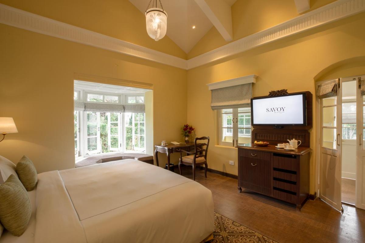 a bedroom with a bed and a flat screen tv at Savoy - IHCL SeleQtions in Ooty