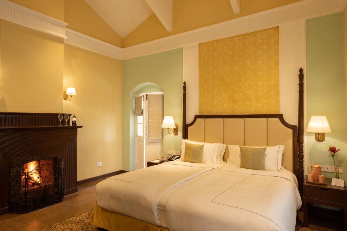 a bedroom with a large bed and a fireplace at Savoy - IHCL SeleQtions in Ooty