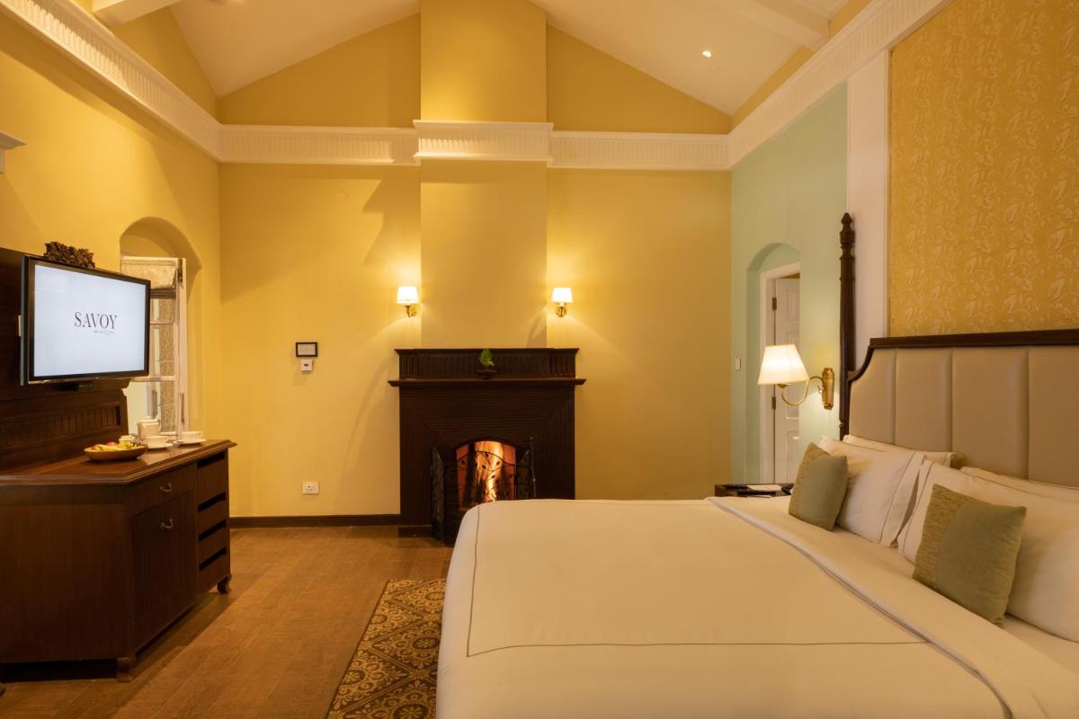 a bedroom with a bed with a fireplace and a television at Savoy - IHCL SeleQtions in Ooty