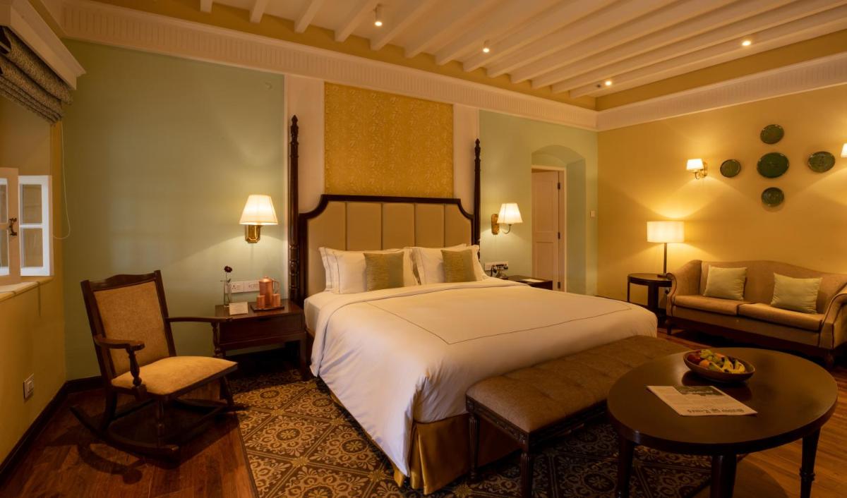 a hotel room with a large bed and a couch at Savoy - IHCL SeleQtions in Ooty