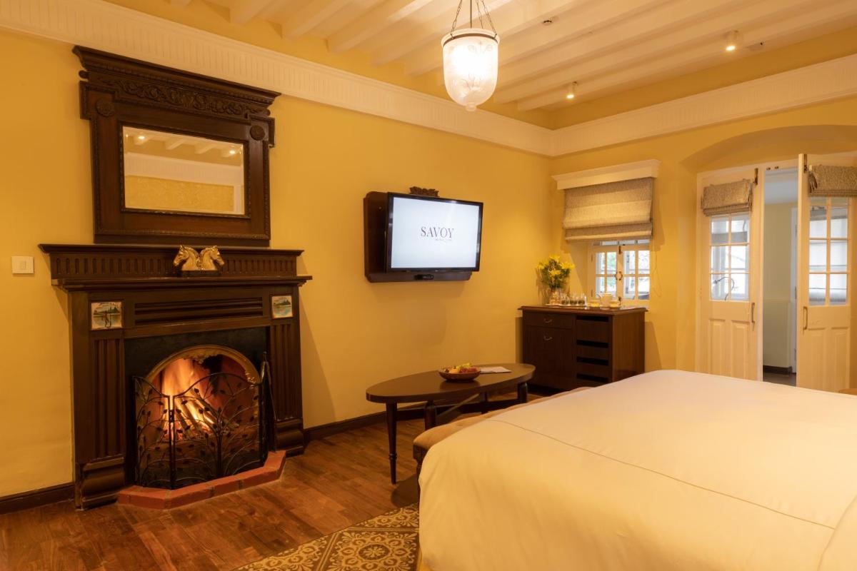 a bedroom with a bed and a fireplace with a tv at Savoy - IHCL SeleQtions in Ooty