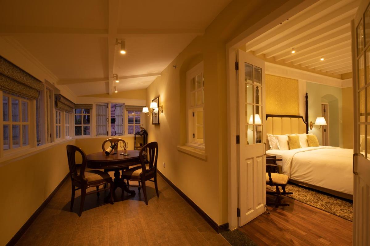 a dining room with a table and a bed at Savoy - IHCL SeleQtions in Ooty