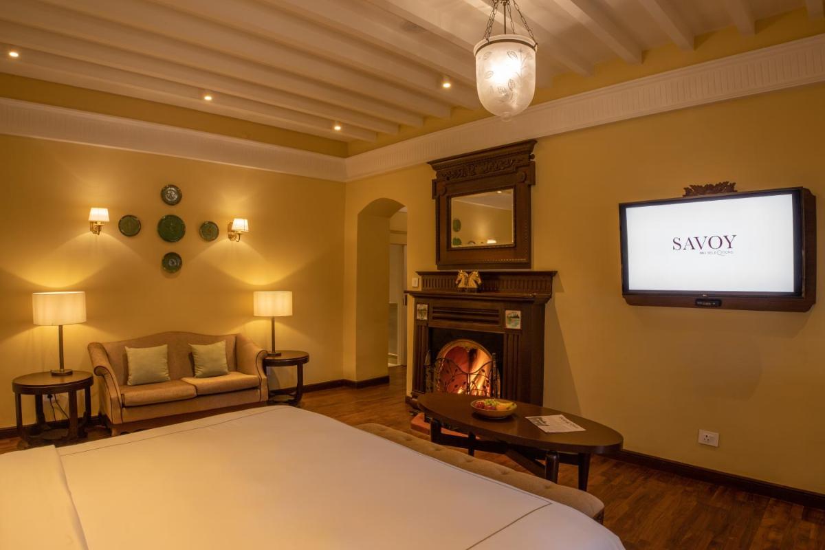 a bedroom with a bed and a tv and a fireplace at Savoy - IHCL SeleQtions in Ooty