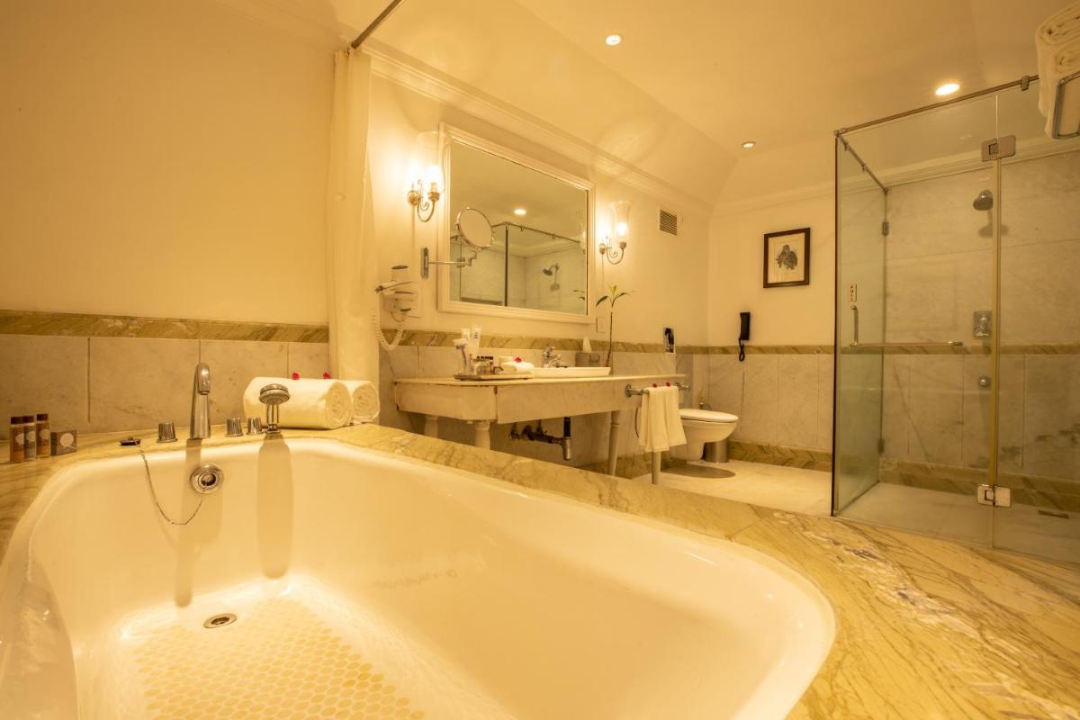 a bathroom with a tub and a sink and a shower at Savoy - IHCL SeleQtions in Ooty