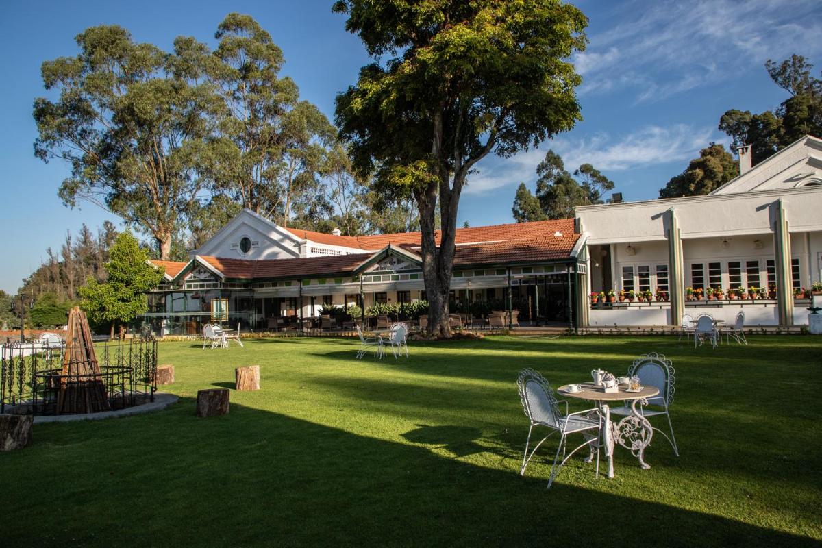 a yard with a table and chairs in front of a building at Savoy - IHCL SeleQtions in Ooty