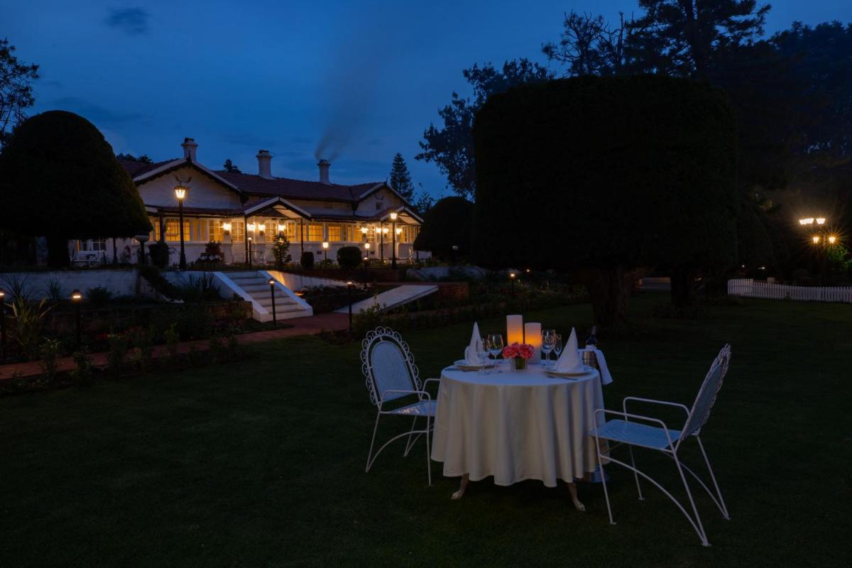 a table and chairs in a yard at night at Savoy - IHCL SeleQtions in Ooty