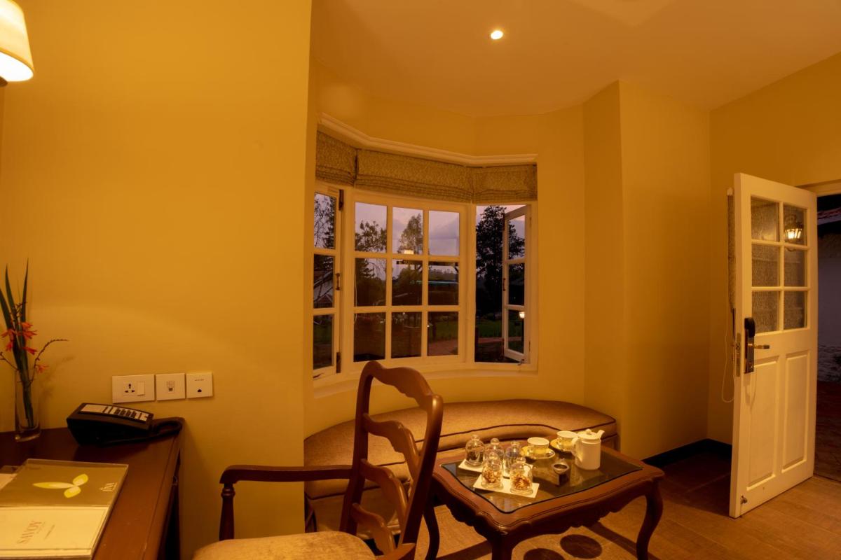 a living room with a table and a chair at Savoy - IHCL SeleQtions in Ooty