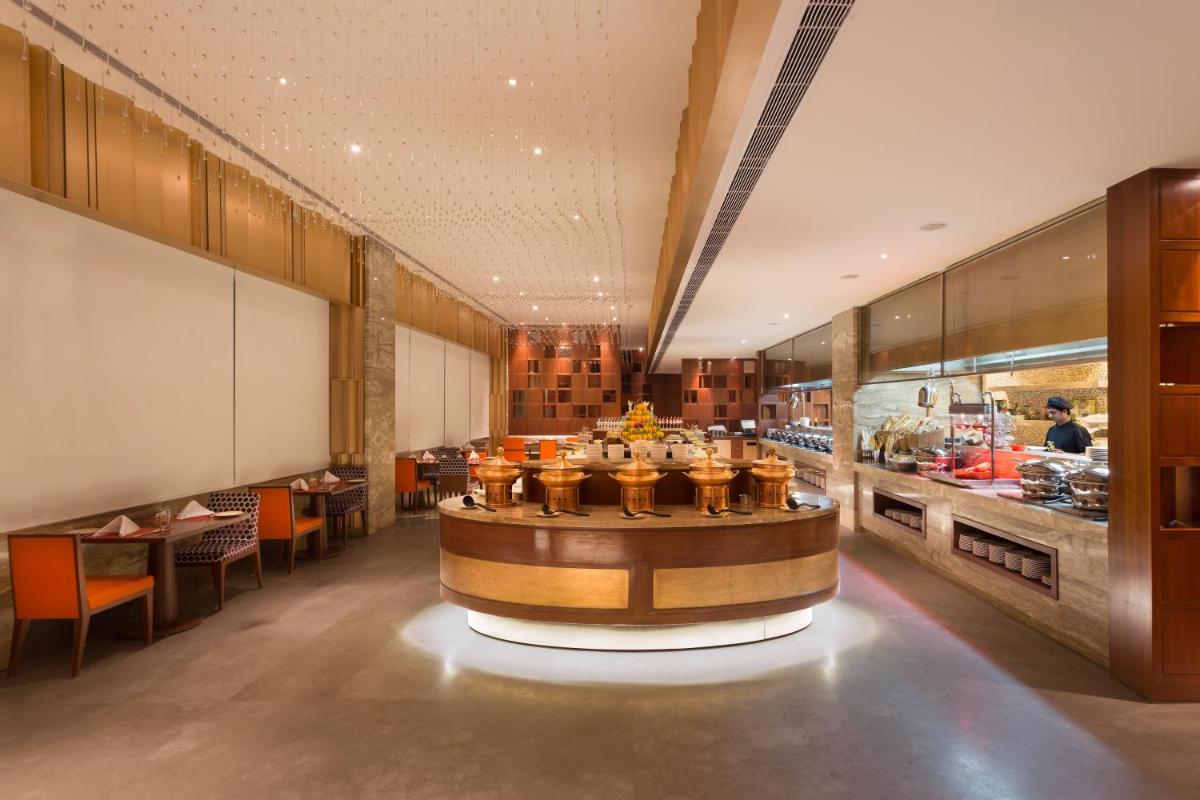 a restaurant with a counter and tables and chairs at Holiday Inn Jaipur City Centre by IHG in Jaipur a restaurant with a counter and tables and chairs at Holiday Inn Jaipur City Centre by IHG in Jaipur