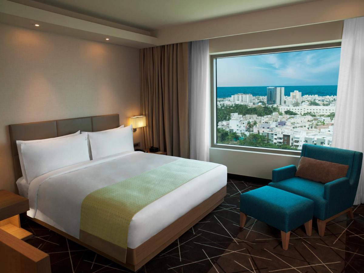 a bedroom with a bed and a chair and a large window at Holiday Inn Chennai OMR IT Expressway by IHG in Chennai