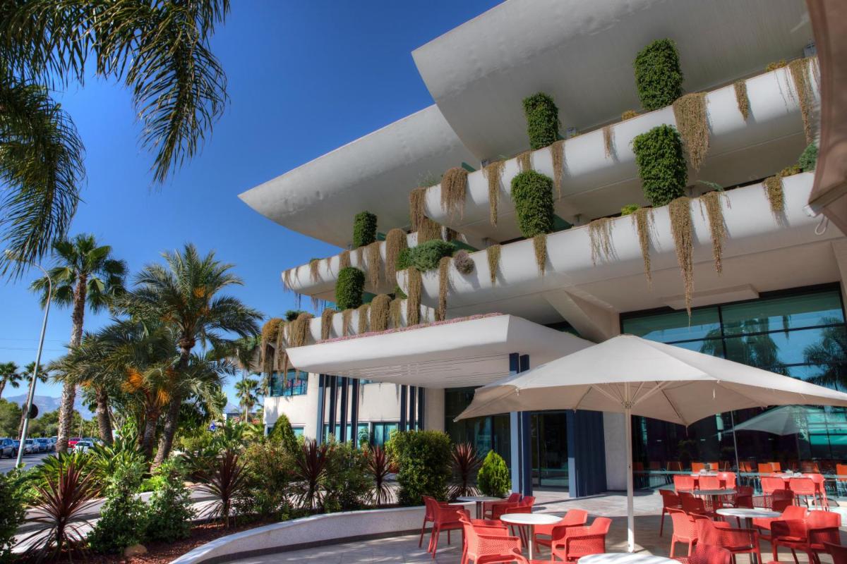 un hotel con mesas y sombrillas frente a un edificio en Hotel Deloix 4* Sup, en Benidorm