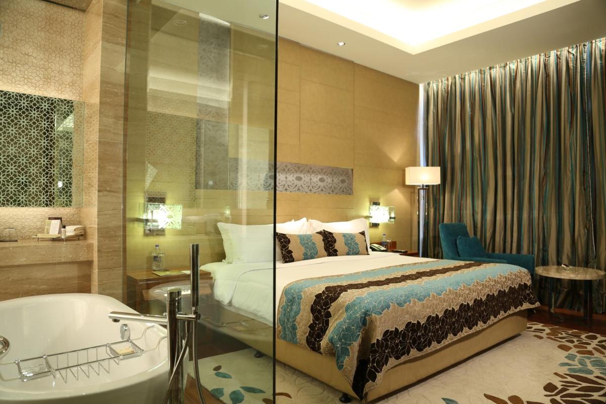 a hotel room with a bed and a bath tub at Taj City Centre Gurugram in Gurgaon