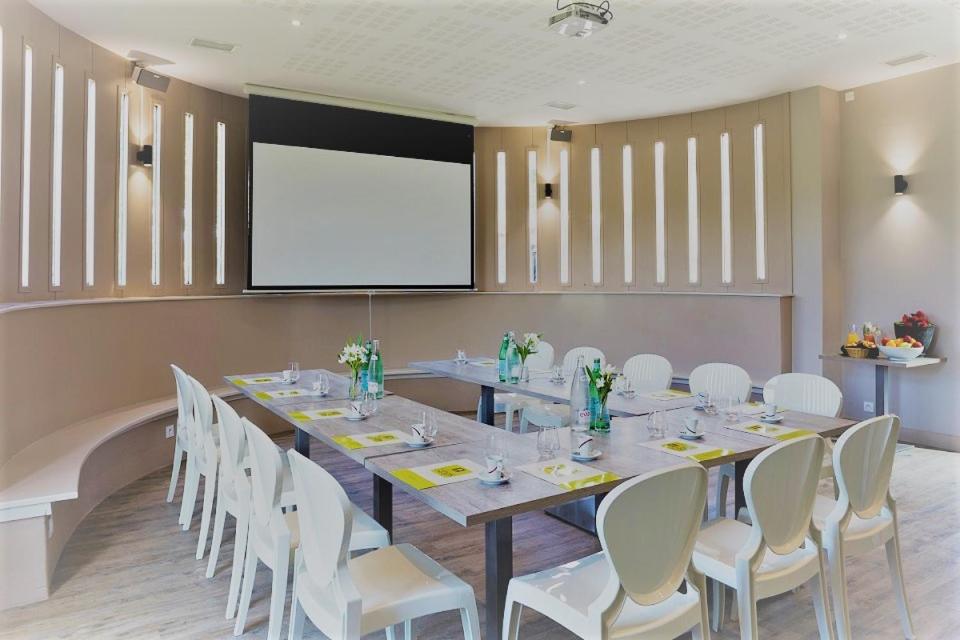 une salle de conférence avec une longue table et des chaises blanches dans l'établissement Logis L'Auberge de Larressingle, à Larressingle 75 autres photos