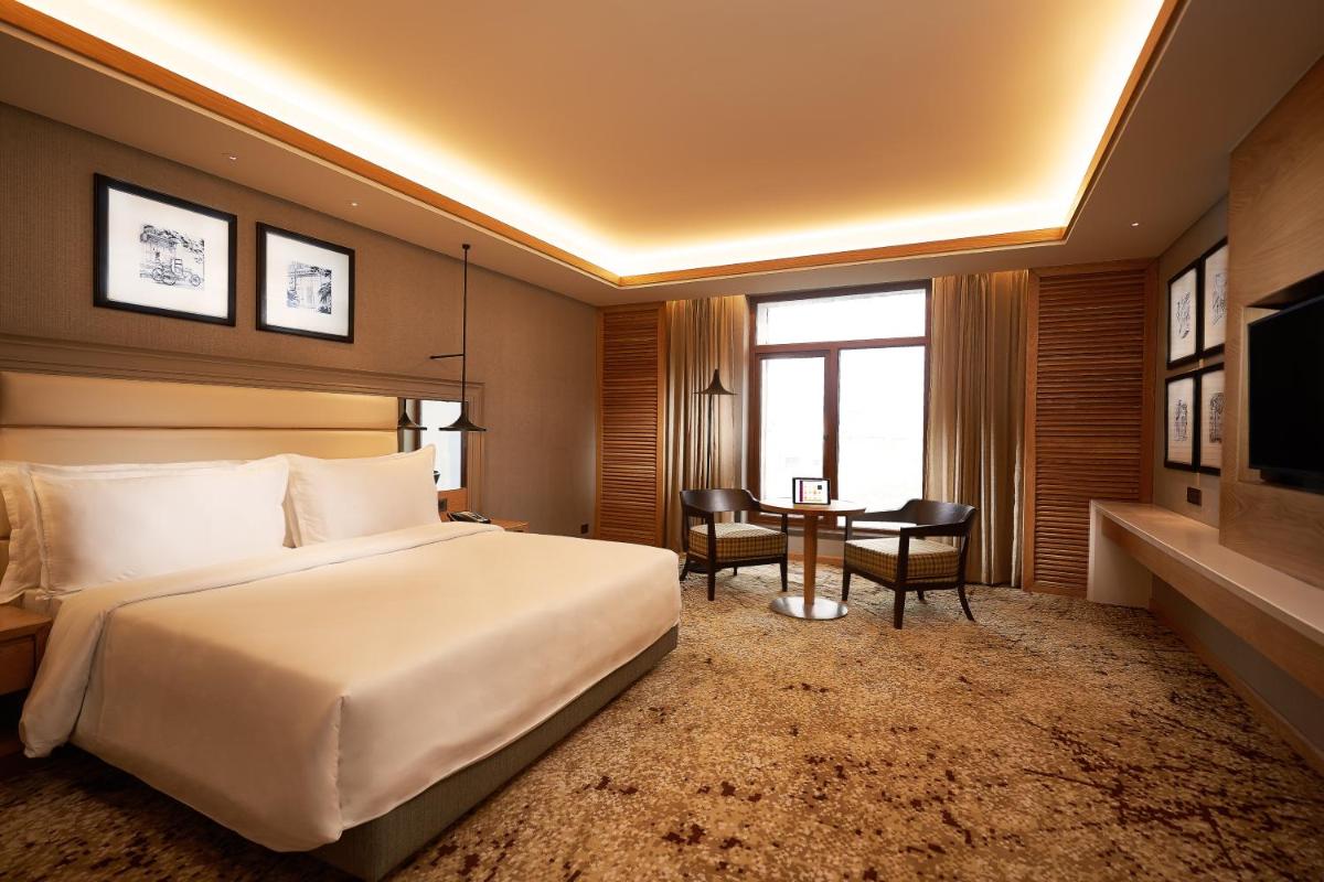 a hotel room with a large bed and a desk at The Residency Towers Puducherry in Puducherry