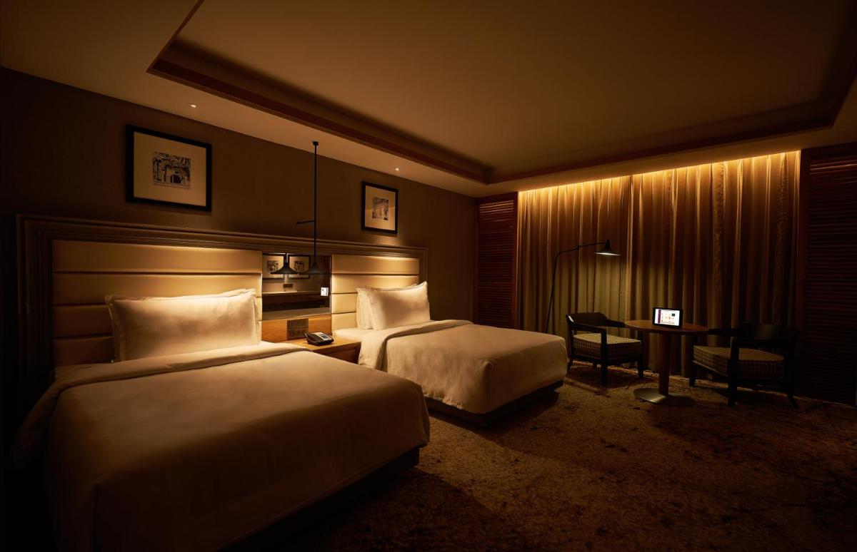 a hotel room with two beds and a table at The Residency Towers Puducherry in Puducherry