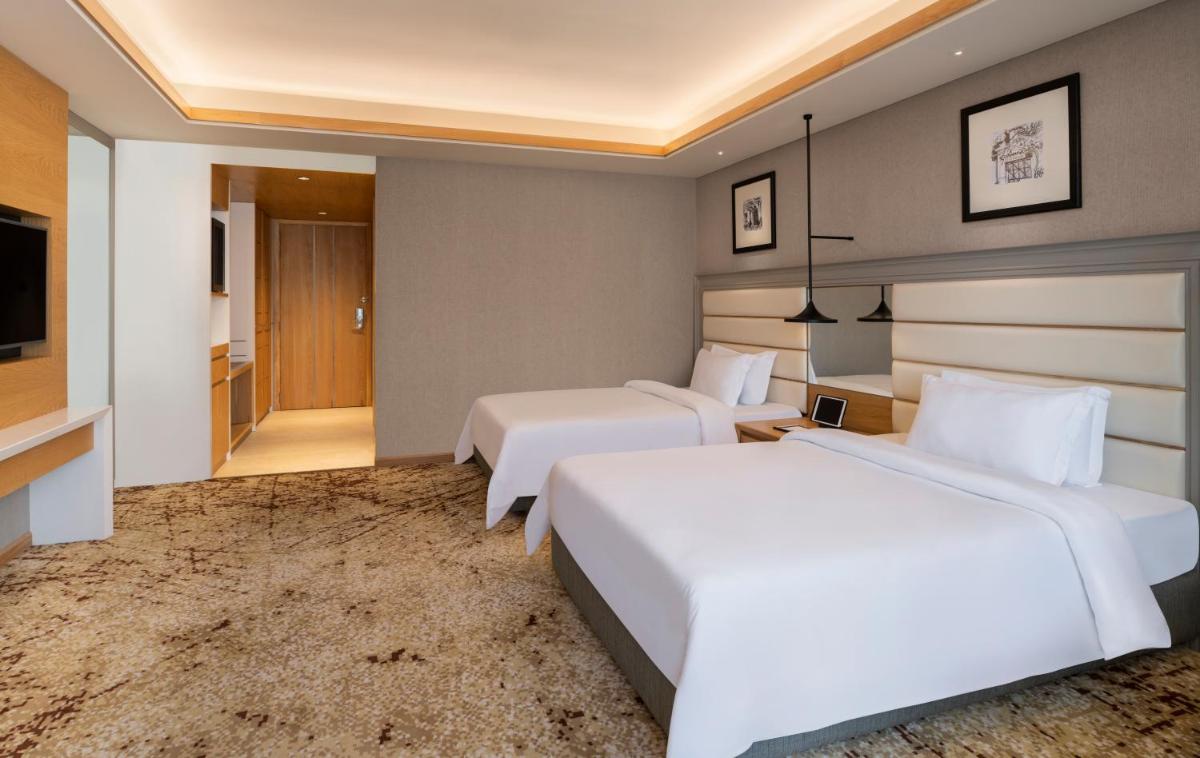 a hotel room with two beds and a television at The Residency Towers Puducherry in Puducherry