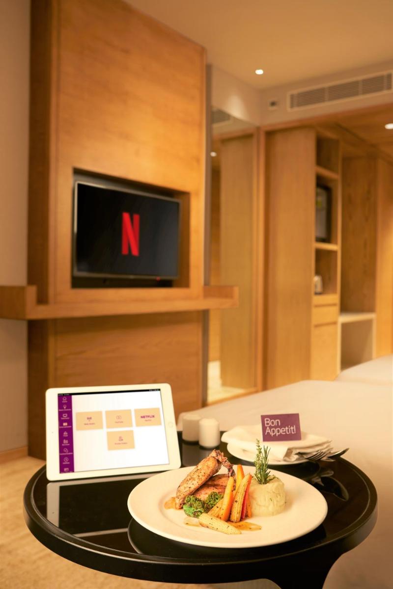 a table with a plate of food and a tablet at The Residency Towers Puducherry in Puducherry