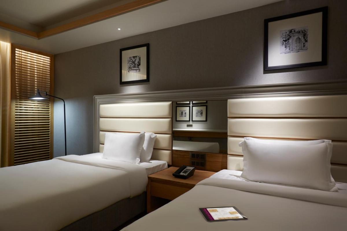 a hotel room with two beds and a lamp at The Residency Towers Puducherry in Puducherry