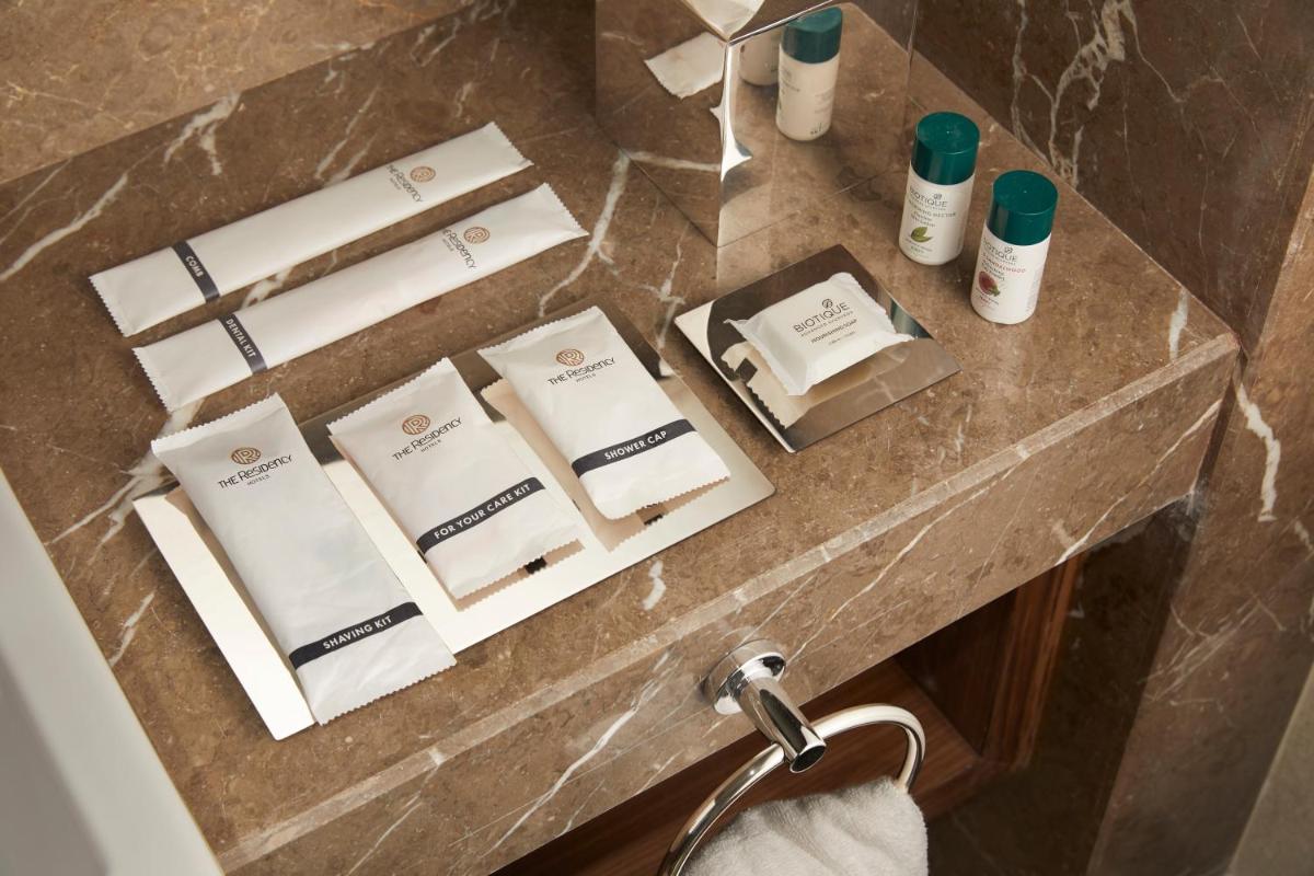 a bathroom counter with towels and products on it at The Residency Towers Puducherry in Puducherry