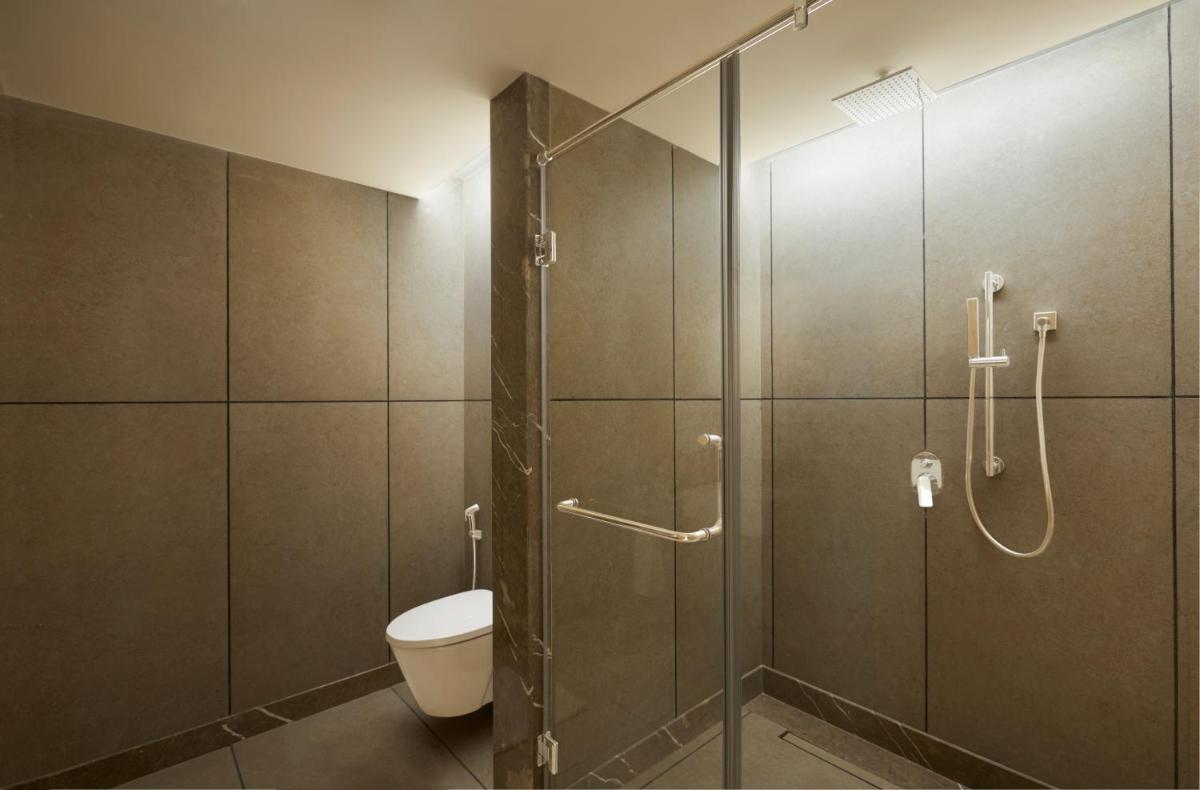 a bathroom with a toilet and a glass shower at The Residency Towers Puducherry in Puducherry