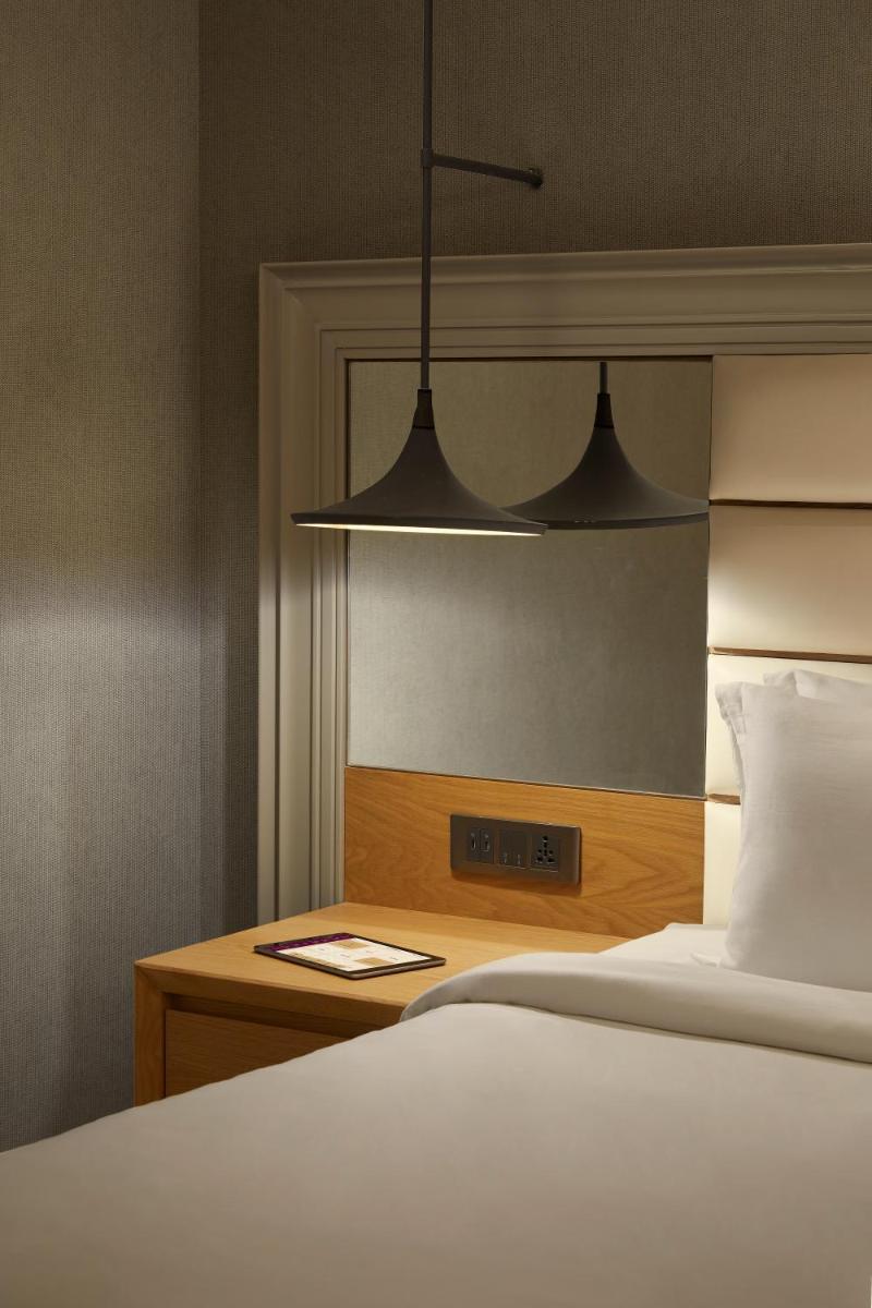 a bedroom with a bed and a desk with a lamp at The Residency Towers Puducherry in Puducherry