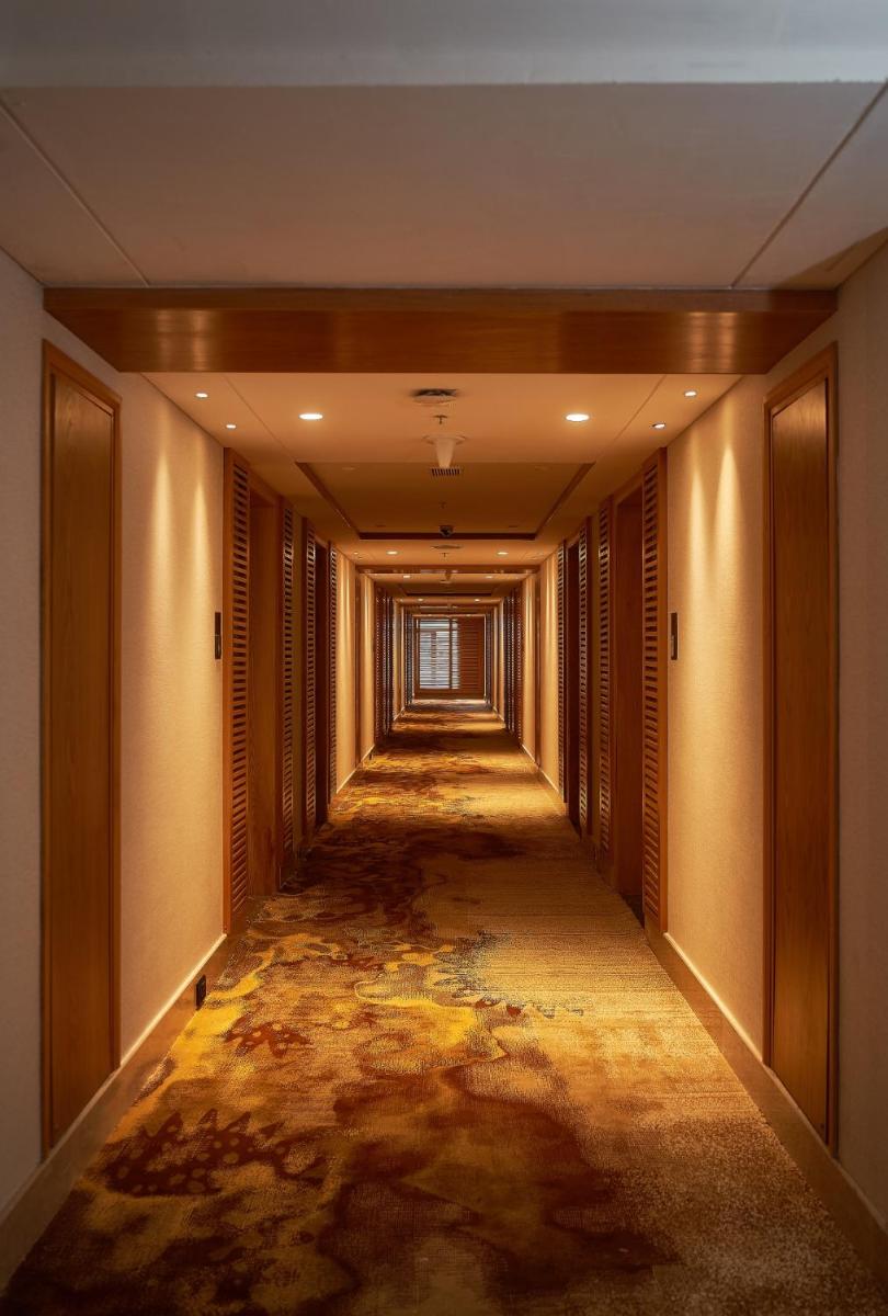 an empty corridor in a building with a painting on the floor at The Residency Towers Puducherry in Puducherry